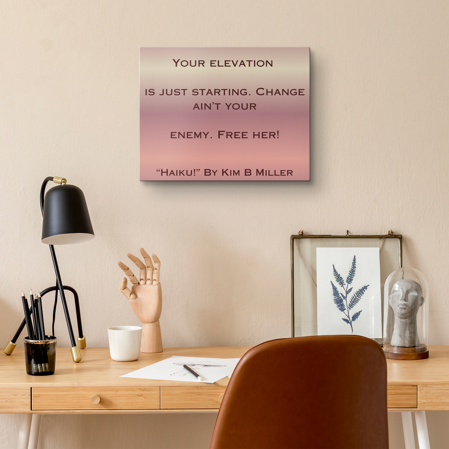 A canvas with a warm rose gold gradient, featuring an original haiku by Kim B Miller, above a desk.